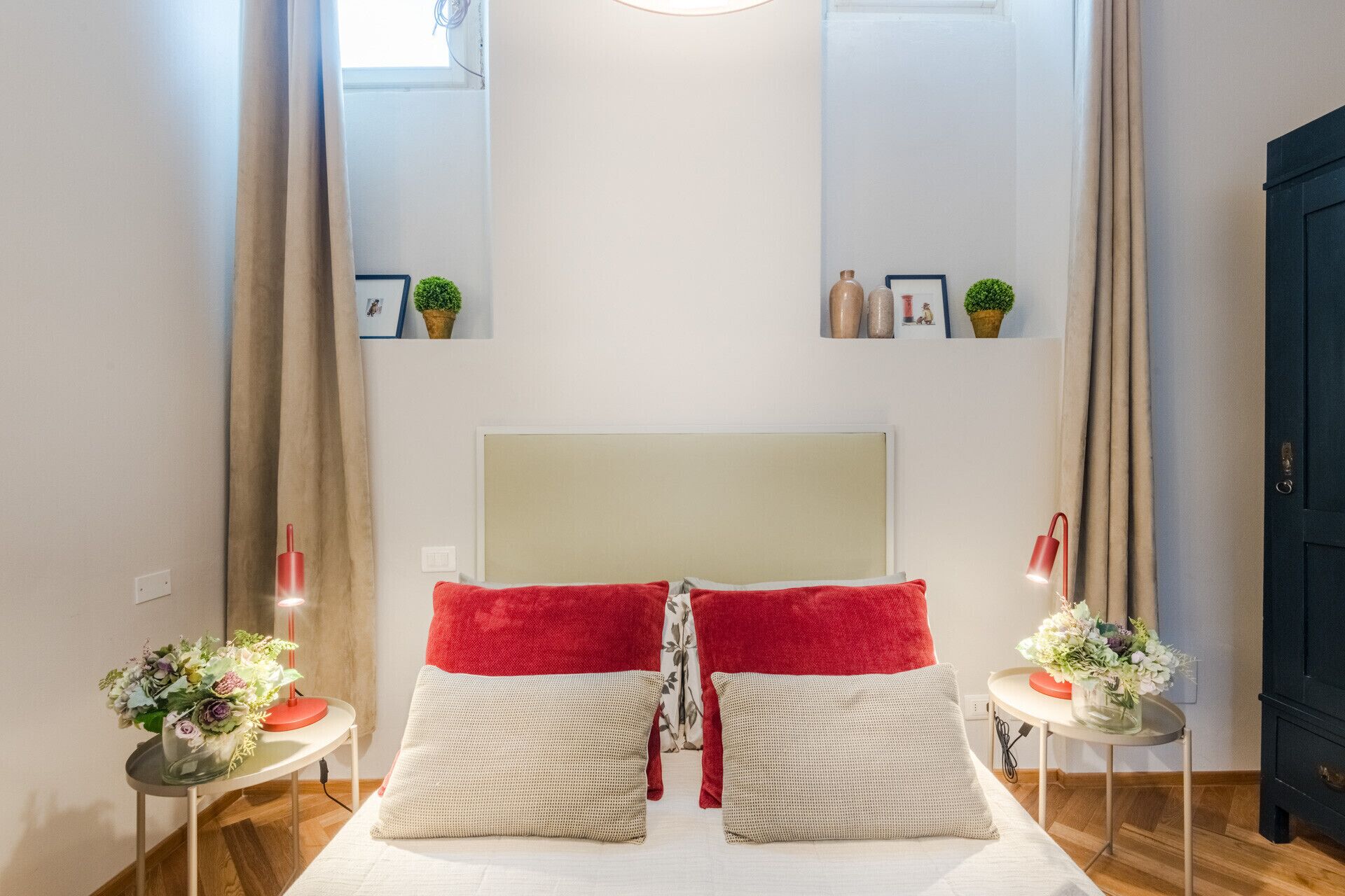 Une chambre à coucher bien rangée, avec un lit placé au centre, entre deux tables de chevet, chacune surmontée d’une petite table et d’une lampe.