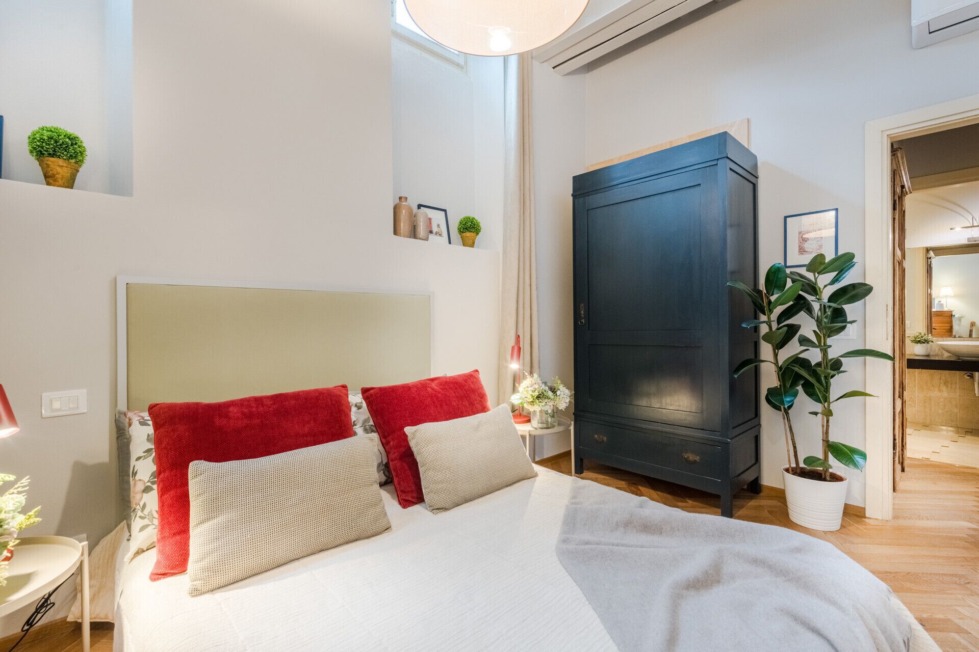 A bedroom with a bed, a wardrobe, and a potted plant.