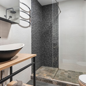 Een moderne badkamer met een grote wastafel, een douchecabine van glas en een betegelde vloer.