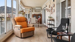 A spacious balcony with a beige sofa, a dining area, and a view of the cityscape. - Los Boliches Sunny Apartment - Ref 120 (Fuengirola)