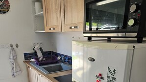 Eine Küche mit Holzausstattung, einem weißen Kühlschrank, einer Mikrowelle und einem Spülbecken.
