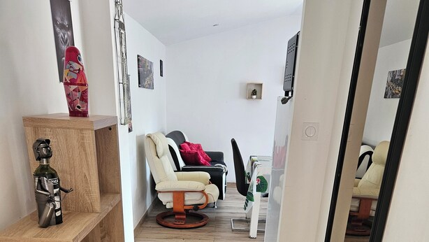 Ein modernes Wohnzimmer mit Holzboden, einer Couch, einem Sessel und einem kleinen Tisch mit einer Dekoration.