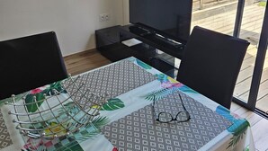 Ein Essbereich mit einem Tisch für zwei Personen, einem Fernseher und Blick auf einen Holzzaun.