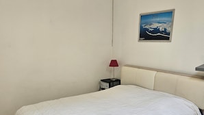 Ein Schlafzimmer mit einem großen Bett, einem Nachttisch mit Lampe und einem gerahmten Bild an der Wand.