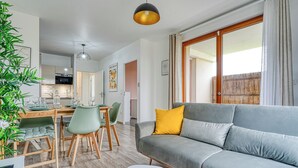 A modern living room with a grey sofa, a dining table with chairs, and a kitchen in the background. - Whole Apartment : Apartment in Residence - Montévrain, France (Montévrain)