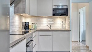 A modern kitchen with white cabinetry, a built-in oven, and a coffee machine. - Whole Apartment : Apartment in Residence - Montévrain, France (Montévrain)