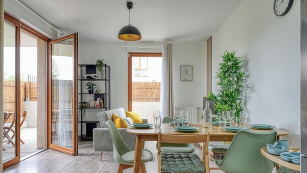 A dining area with a wooden table set for four, surrounded by chairs with cushioned seats. - Whole Apartment : Apartment in Residence - Montévrain, France (Montévrain)