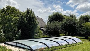A greenhouse structure with a curved roof, surrounded by a grassy area and trees. - Farmhouse in the heart of the Loire castles (VILLEMARDY)