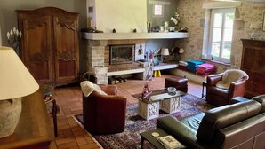 A cozy living room with a fireplace, leather sofas, a coffee table, and a stone wall. - Farmhouse in the heart of the Loire castles (VILLEMARDY)