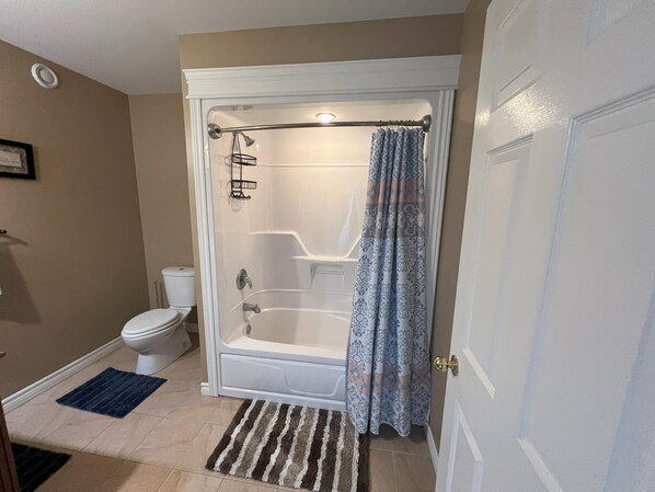 A bathroom with a walk-in shower, toilet, and a blue patterned shower curtain. - Bright & Spacious apartment (Mount Pearl)