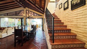 Un vaste espace de vie comprenant une table à manger, des canapés et un escalier dont les marches sont décorées de motifs.