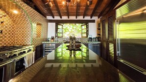Une cuisine moderne dotée d’un îlot central, d’un luminaire suspendu et offrant une vue sur la verdure à l’extérieur.
