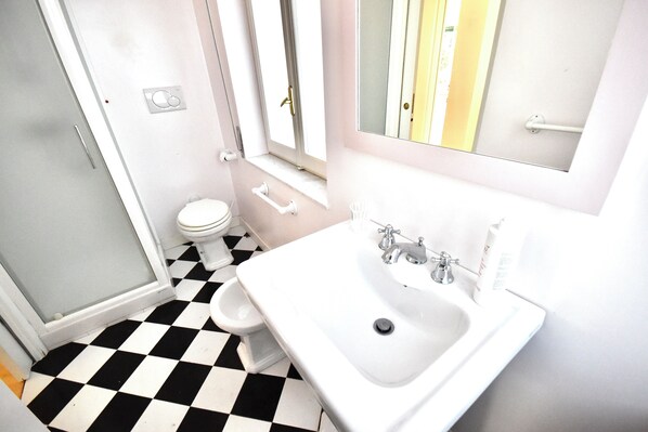 Une salle de bain avec un carrelage à motifs géométriques, un lavabo blanc et des toilettes.