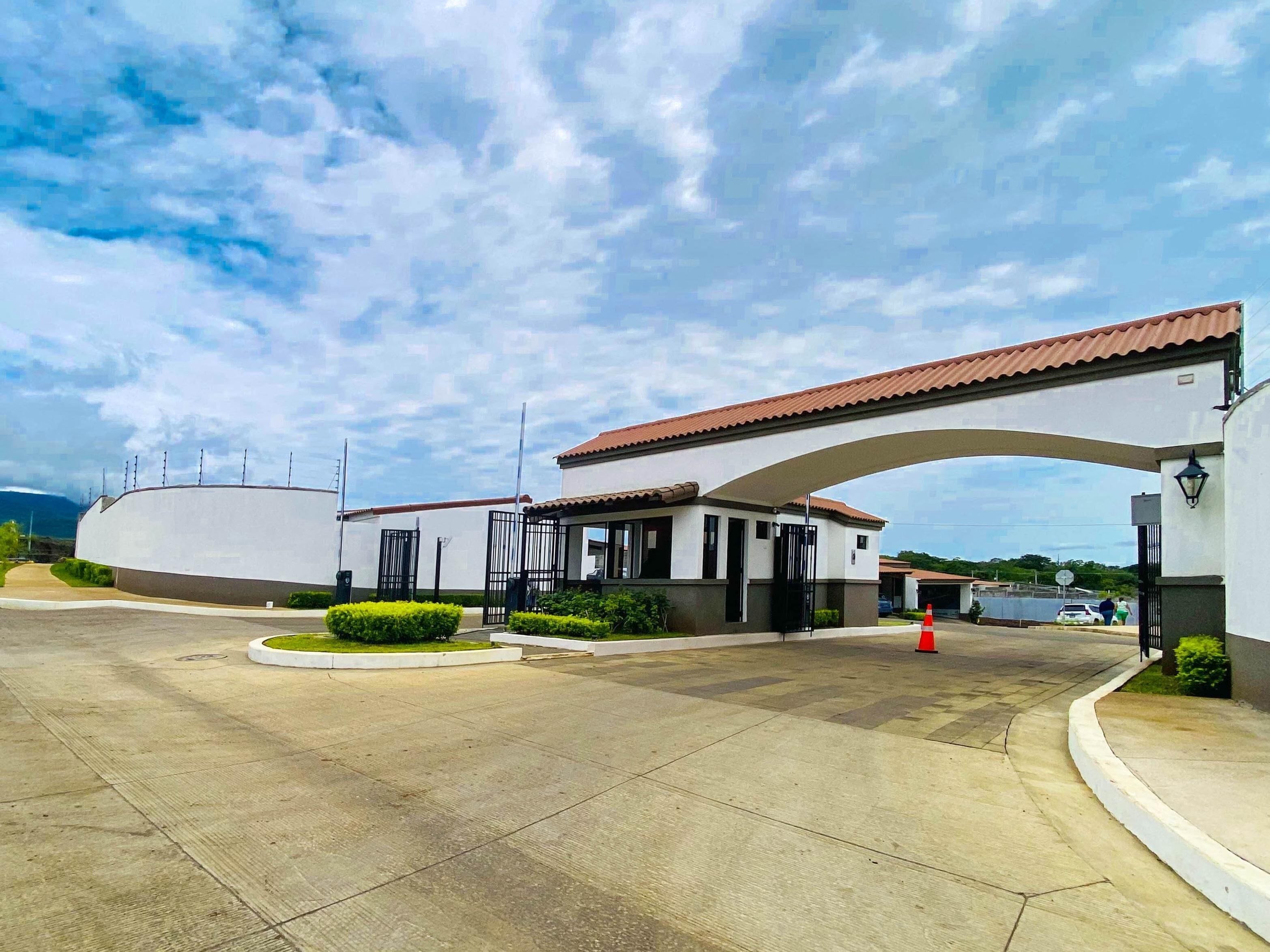 Un edificio con un amplio acceso en arco, una zona de espera cubierta y un estacionamiento.