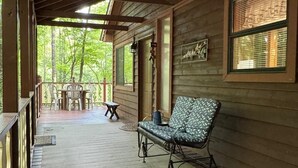 A wooden porch with a bench, a table, and chairs. - My Cabin In The Mountain (Otto)