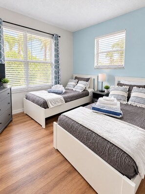A bedroom with two beds, a dresser, and a nightstand with a lamp. - Sandy Feet Retreat 1A - Minutes to Sanibel - Pool - fast WiFi - free Parking (Fort Myers)