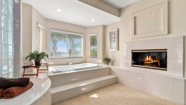 A modern bathroom with a bathtub, a fireplace, and a window with blinds. - Waterfront Lakeside Mansion Great for Large Families, Retreat, and Events  (Lake Elsinore)