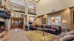 A spacious living area with a fireplace, a large sofa set, and a staircase leading to an upper level. - Waterfront Lakeside Mansion Great for Large Families, Retreat, and Events  (Lake Elsinore)