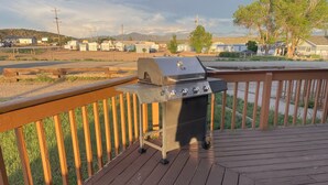 A barbecue grill on a wooden deck with a view of a rural area in the background. - Main Street Cabin near Sand Dunes - Fort Garland (Fort Garland)
