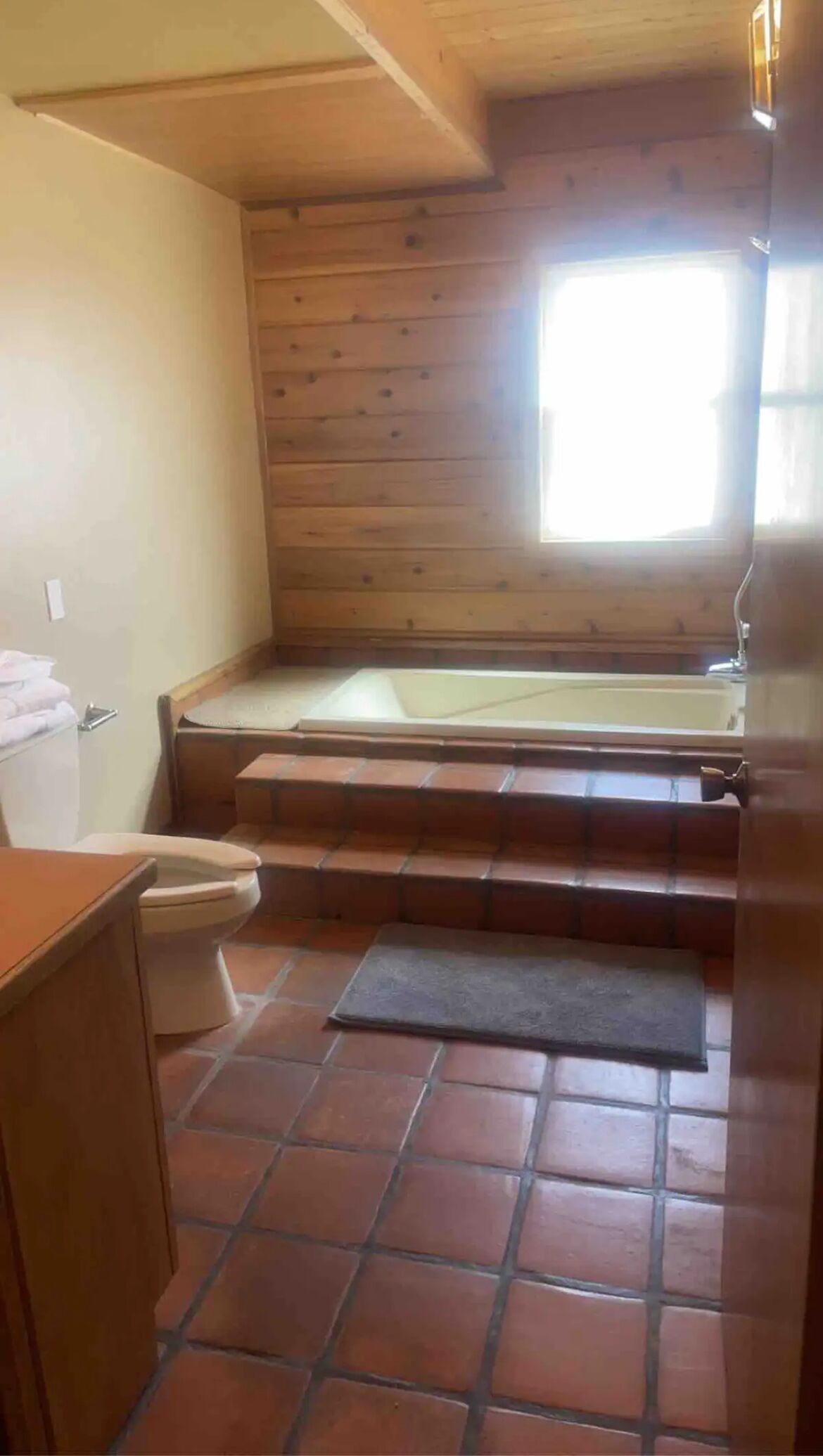A small, compact bathroom with a wooden floor, a toilet, a sink, and a bathtub.