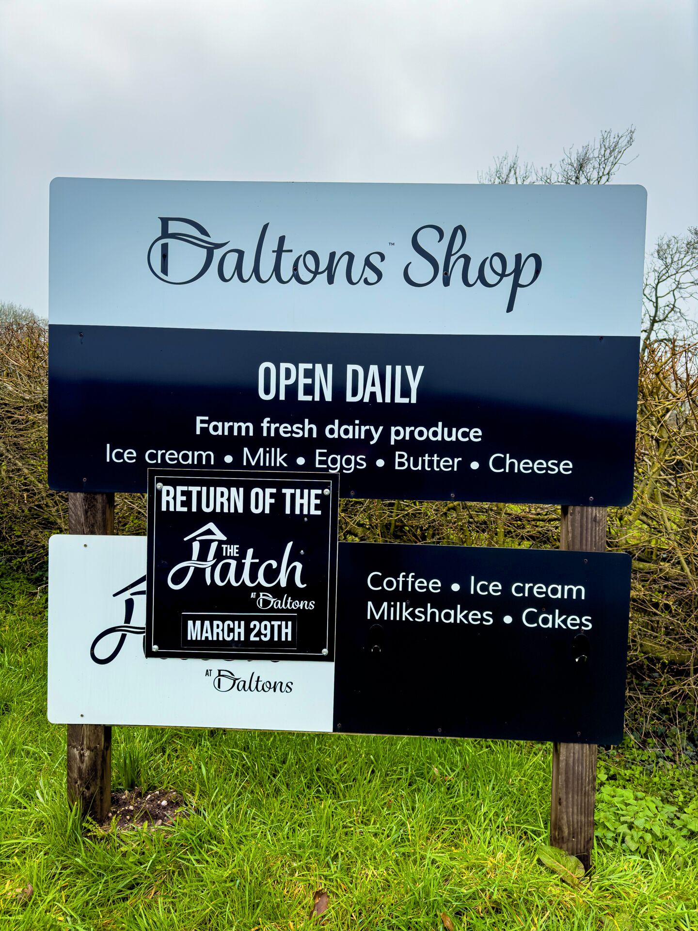 Señal de una tienda llamada 'Saltons Shop' con una lista de productos lácteos frescos de granja y otros artículos.