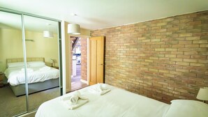 Ein Hotelzimmer mit einem großen Bett, einer Schiebetür zum Balkon und einer Ziegelwand.