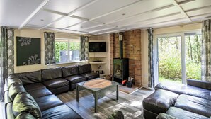 Ein modernes Wohnzimmer mit einem Ecksofa, einem Holztisch, einem Flachbildfernseher und einem Kamin aus Backsteinen.