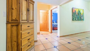 Un couloir avec une armoire en bois, un sol carrelé et un tableau accroché au mur.