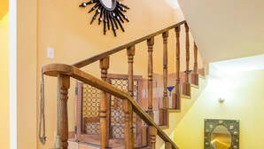 Un escalier en bois avec une rampe, un miroir décoratif et un mur orné de motifs.