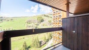 Ein Balkon mit Blick auf ein grünes Tal und ein mehrstöckiges Gebäude im Hintergrund.