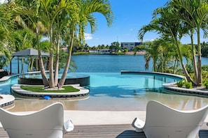 A pool area with palm trees, lounge chairs, and a view of the water. - Wonderlake 7BR Resort • Pool & BBQ • Luxury Stay (Miami)