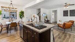 Uma cozinha moderna com bancada de granito, armários de madeira escura e área de jantar com cadeiras de couro.