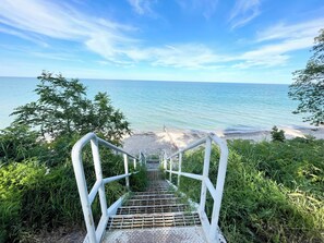 Escada que leva a uma praia, com vista clara para o oceano.