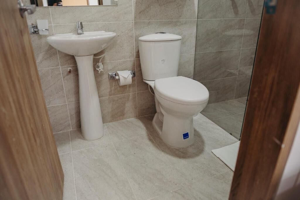 A bathroom with a pedestal sink, toilet, and a shower area.