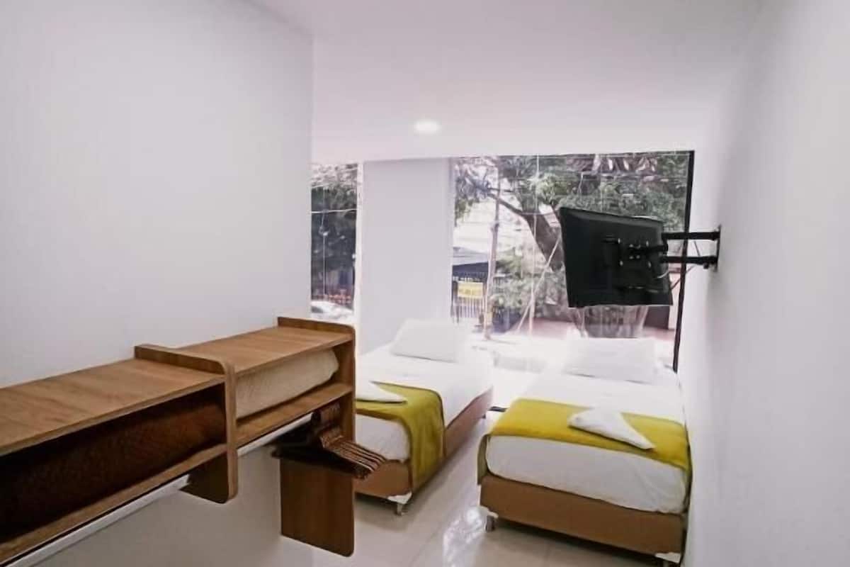 Camera da letto moderna con due letti, una scrivania in legno e un'ampia finestra.
