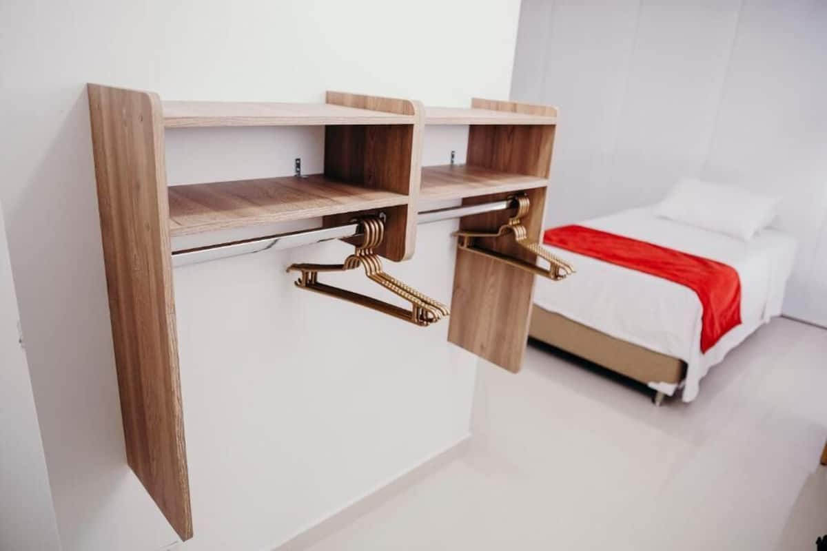 Una camera da letto con un letto, una parete bianca e una scrivania in legno con cassetti.