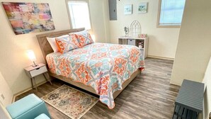Une chambre à coucher comprenant un lit, des tables de chevet, une chaise, un tapis et des œuvres d’art accrochées aux murs.