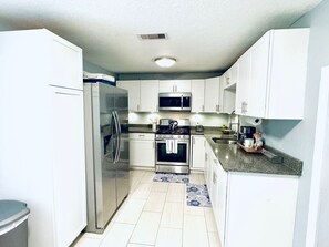 A compact kitchen with white cabinets, stainless steel appliances, and a granite countertop. - Relax & Unwind in 2BR 1BA Home in Quiet Neighborhood (Nederland)