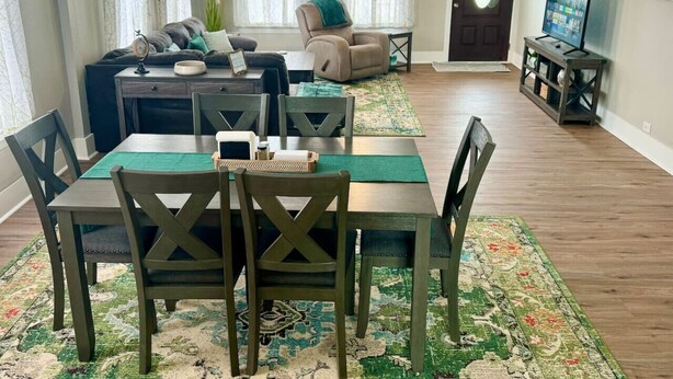 A dining area with a table and chairs, a sofa, and a television in the background. - Bright & Airy 2BR 1BA Home Near The Riverfront (Port Neches)