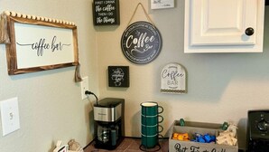 A kitchen with a coffee station, including a coffee maker, mugs, and coffee beans. - Bright & Airy 2BR 1BA Home Near The Riverfront (Port Neches)