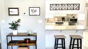 A modern kitchen with a central island, two bar stools, and a decorative wall panel.