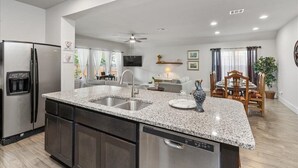 A modern kitchen with granite countertops, stainless steel appliances, and a dining area with a wooden table and chairs. - Perfect house for vacation or work w/Patio, Yard & Parking! 5 min from Kalahari! (Round Rock)