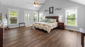 A bedroom with a large bed, a ceiling fan, and multiple windows. - Farmhouse at Magnolia Valley (Fort Valley)