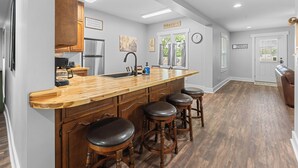 A modern kitchen with a central island, bar stools, and a large window. - Farmhouse at Magnolia Valley (Fort Valley)