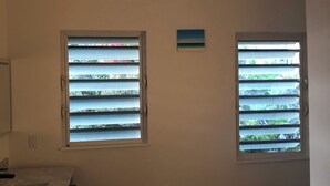 A room with two windows, a small blue sign, and a white ceiling.