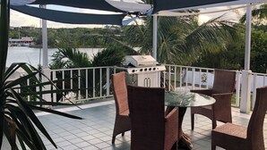 An outdoor patio with a grill, wicker chairs, and a view of the water.