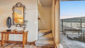 Een trap leidt naar een balkon met uitzicht op een strand en een hek.