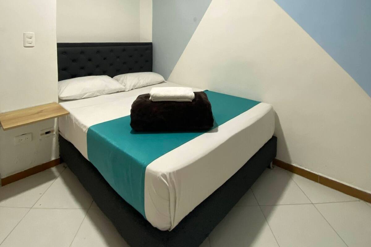 A bedroom with a bed, a nightstand, and a wall with a geometric design.