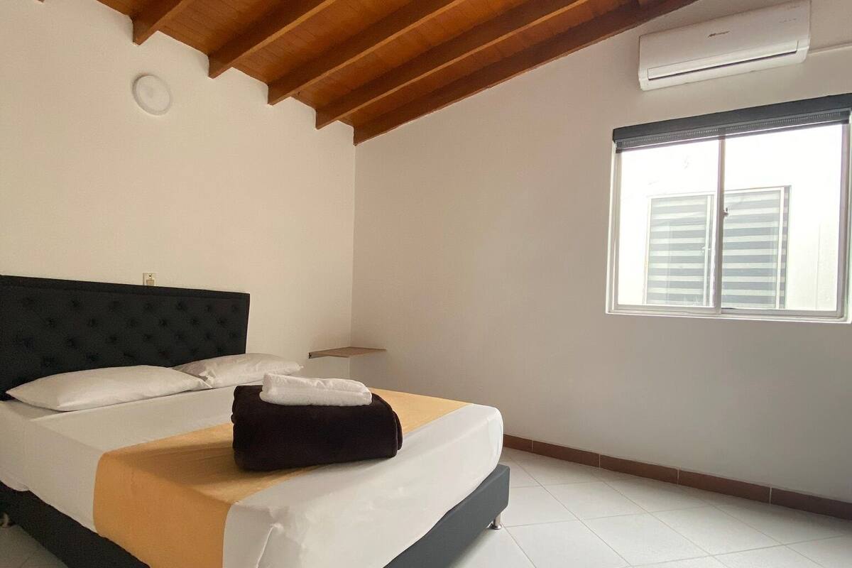 A bedroom with a bed, a window, and a ceiling fan.