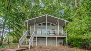 A two-story cabin with a balcony, surrounded by dense forest. - Dewitt -Cozy cabin in the woods- perfect for a small family and a dog near SML State Park (Huddleston)